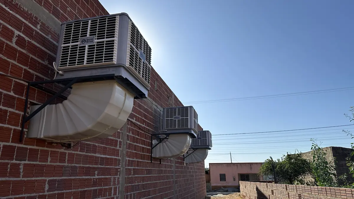 Três climatizadores Tecno Brisa instalados na parede externa de um comércio, com dutos curvos levando o ar para dentro
